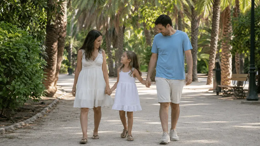 Familia caminando de la mano por un paseo con palmeras y vegetación en Málaga